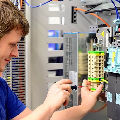 Ein Elektroniker der an einer Reihenklemme schraubt